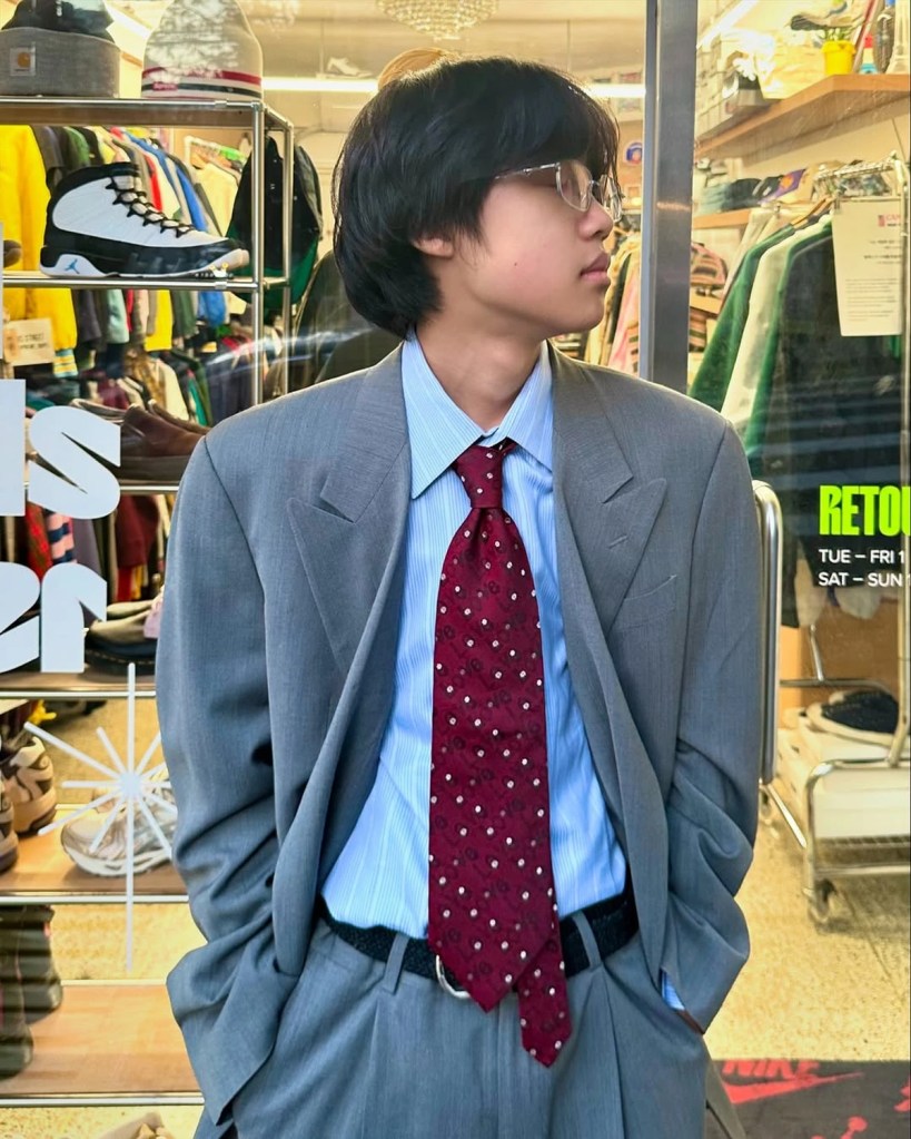 A young man in an oversized gray suit and red tie, styled with a retro aesthetic at Retouch Seoul