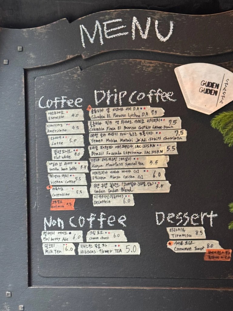 A chalkboard menu at Guden Guden Cafe in Yongsan, Seoul, displaying a selection of specialty drip coffee, espresso drinks, non-coffee beverages, and desserts.
