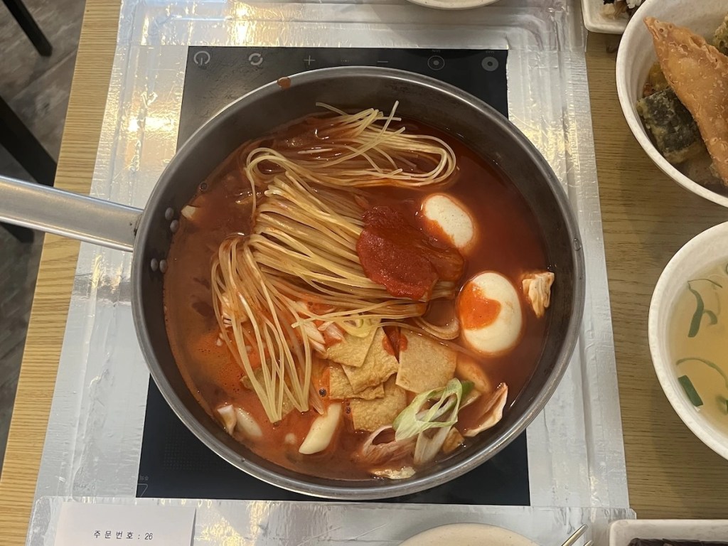 Jukseok tteokbokki cooking at the table with ramen, rice cakes, and spicy red sauce