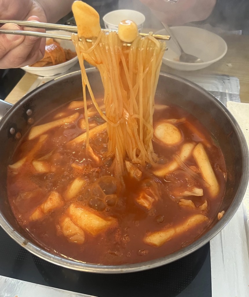 Jukseok tteokbokki cooking at the table with ramen, rice cakes, and spicy red sauce